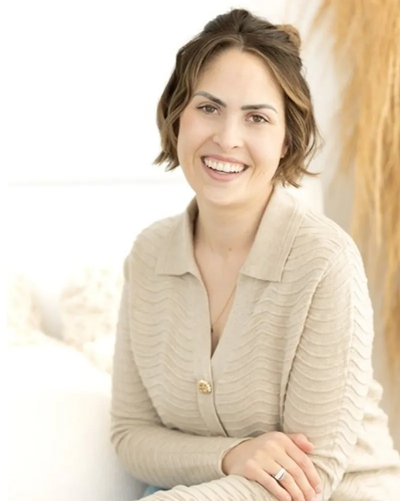 Pediatric sleep consultant Jenna Phan of Phan of Sleep in Calgary, smiling in a cream knit cardigan